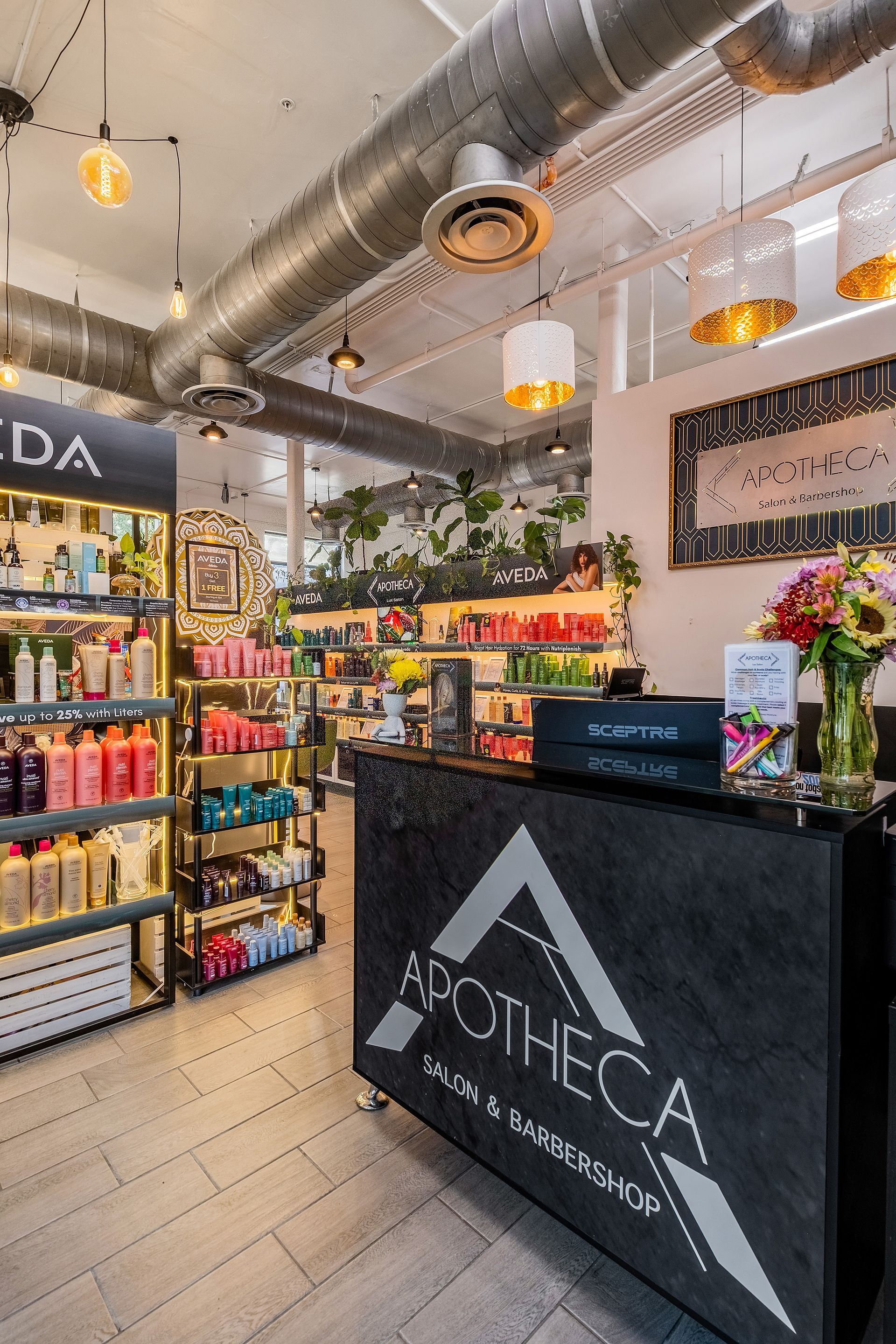 Salon interior with black reception desk, retail shelves, and decorative lighting.