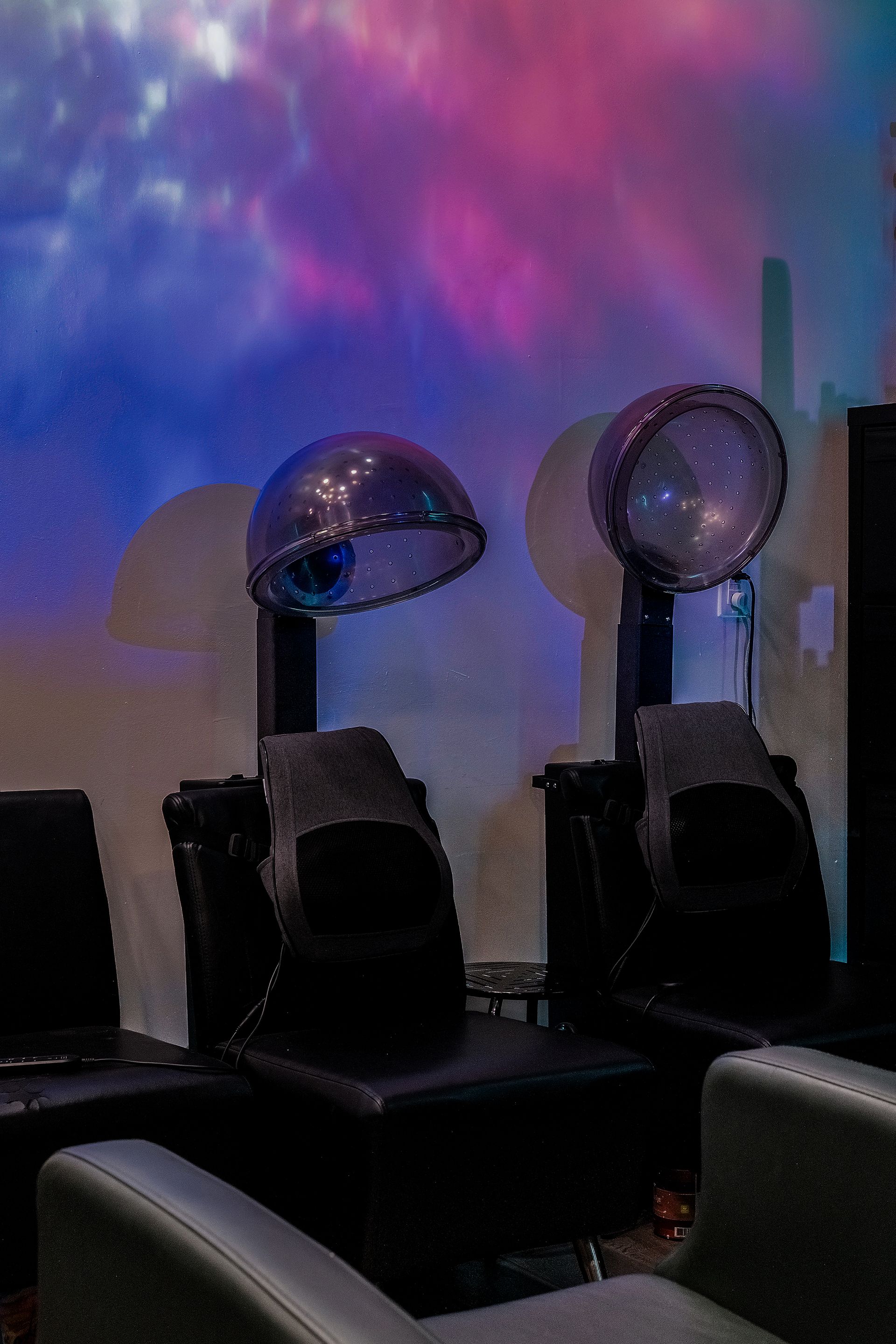 Two hair dryer chairs under colorful, stylized wall art.