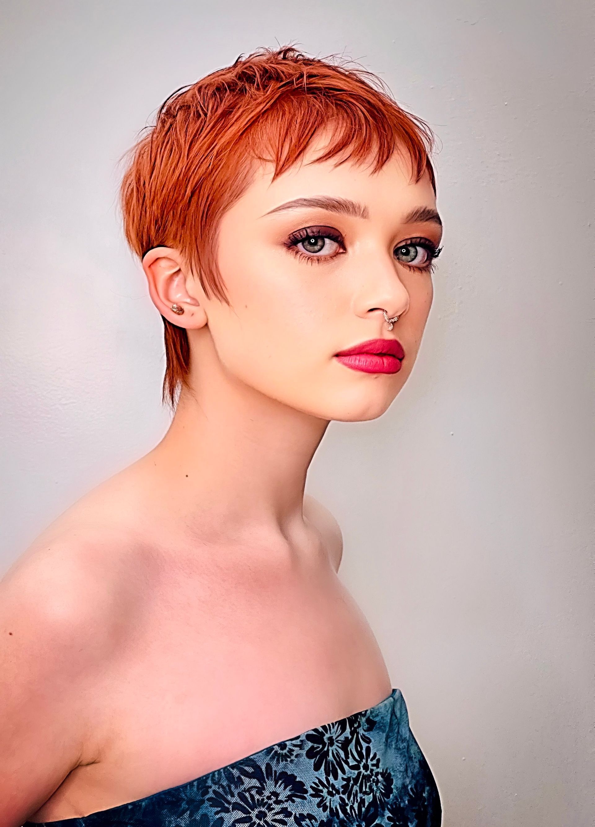 A woman with short red hair and a nose ring