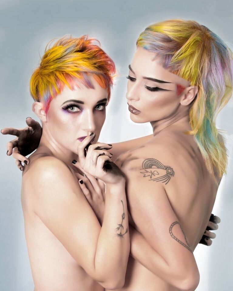 Two women with colorful hair are hugging each other.