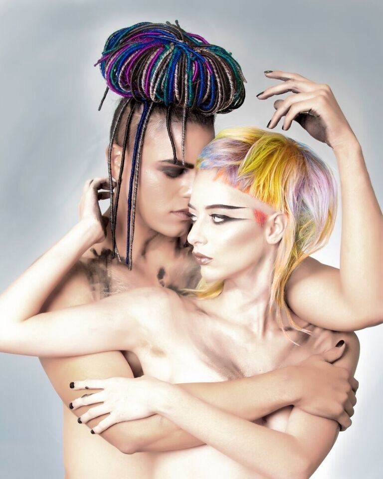 A man and a woman with colorful hair are hugging each other.
