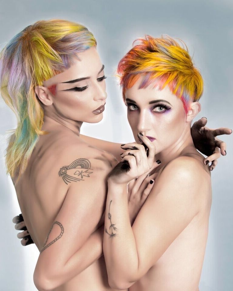 Two women with colorful hair are hugging each other.