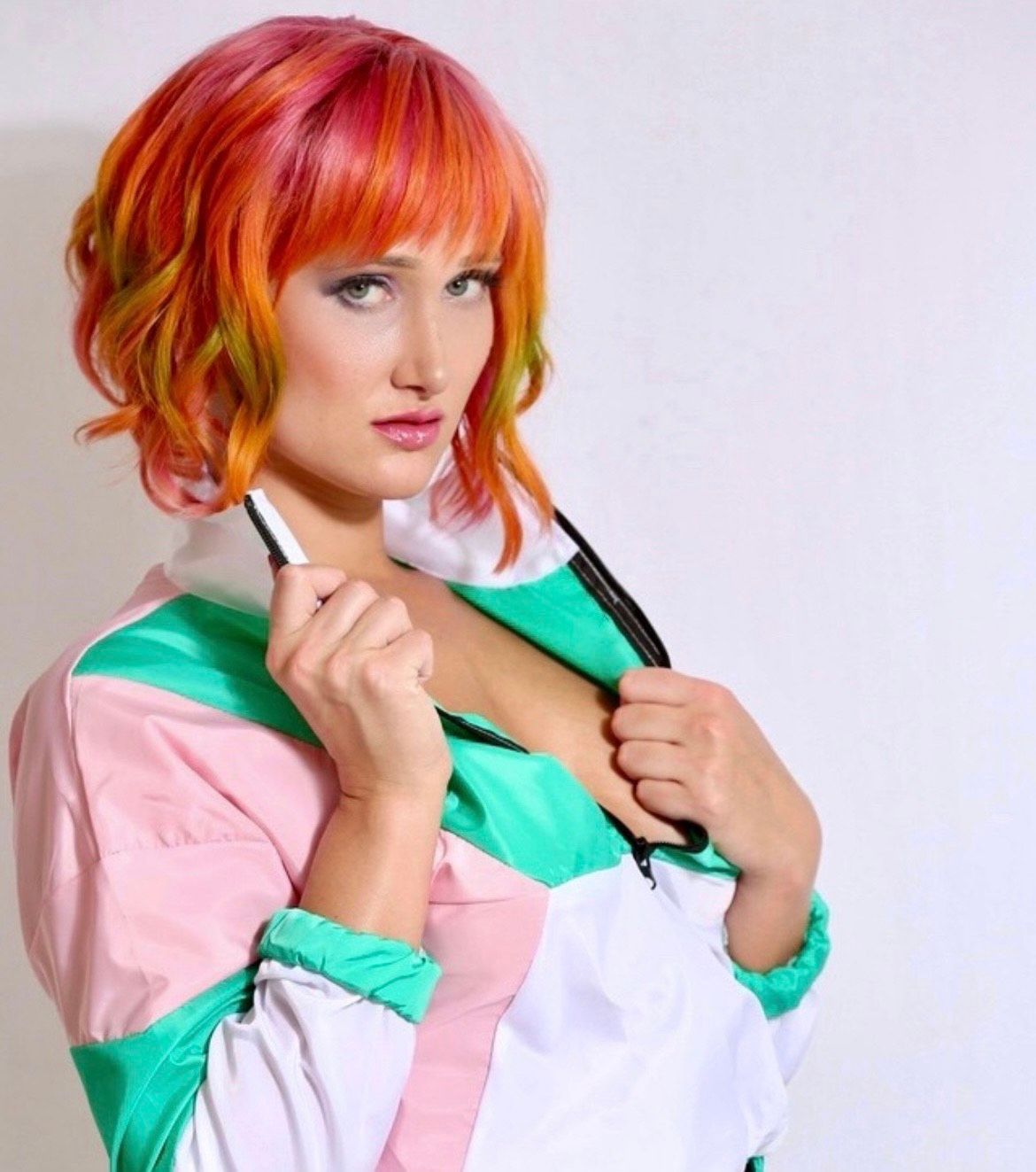 A woman with red hair is wearing a pink and green jacket