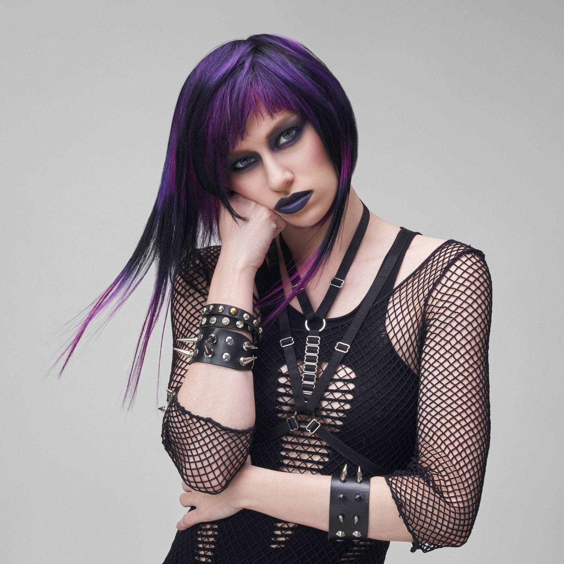 A woman with purple hair is wearing a black dress