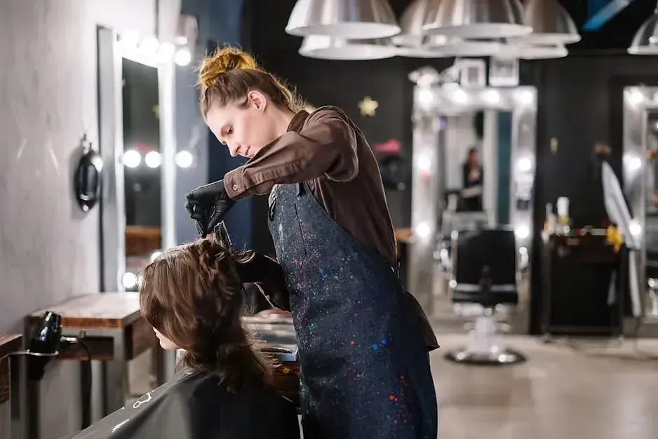A woman is getting her hair blow dried by a hairdresser in a salon.