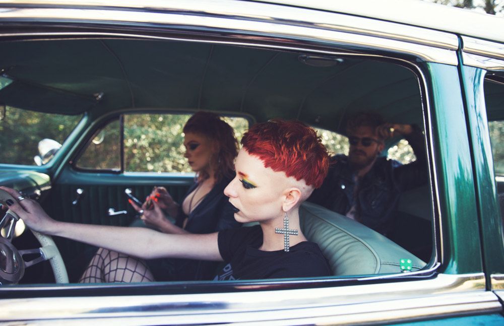 A group of people are sitting in a car looking at their phones.