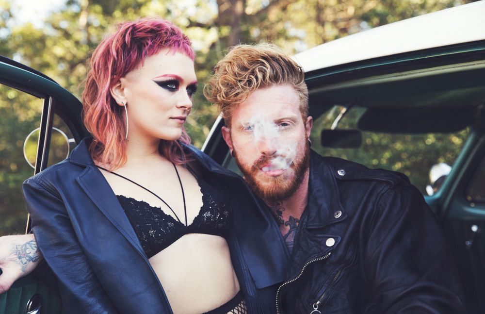 A man and a woman are standing next to each other in a car.