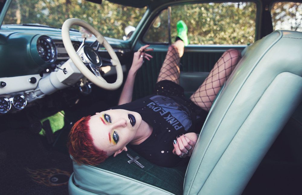 A woman is laying in the driver 's seat of a car.