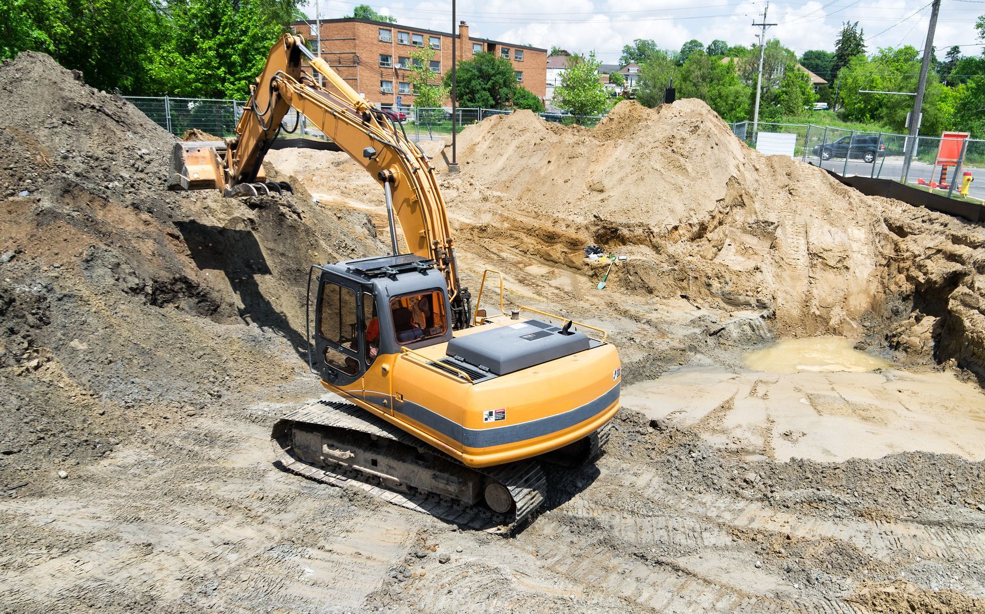 a yellow excavator is digging a hole in a pile of dirt .