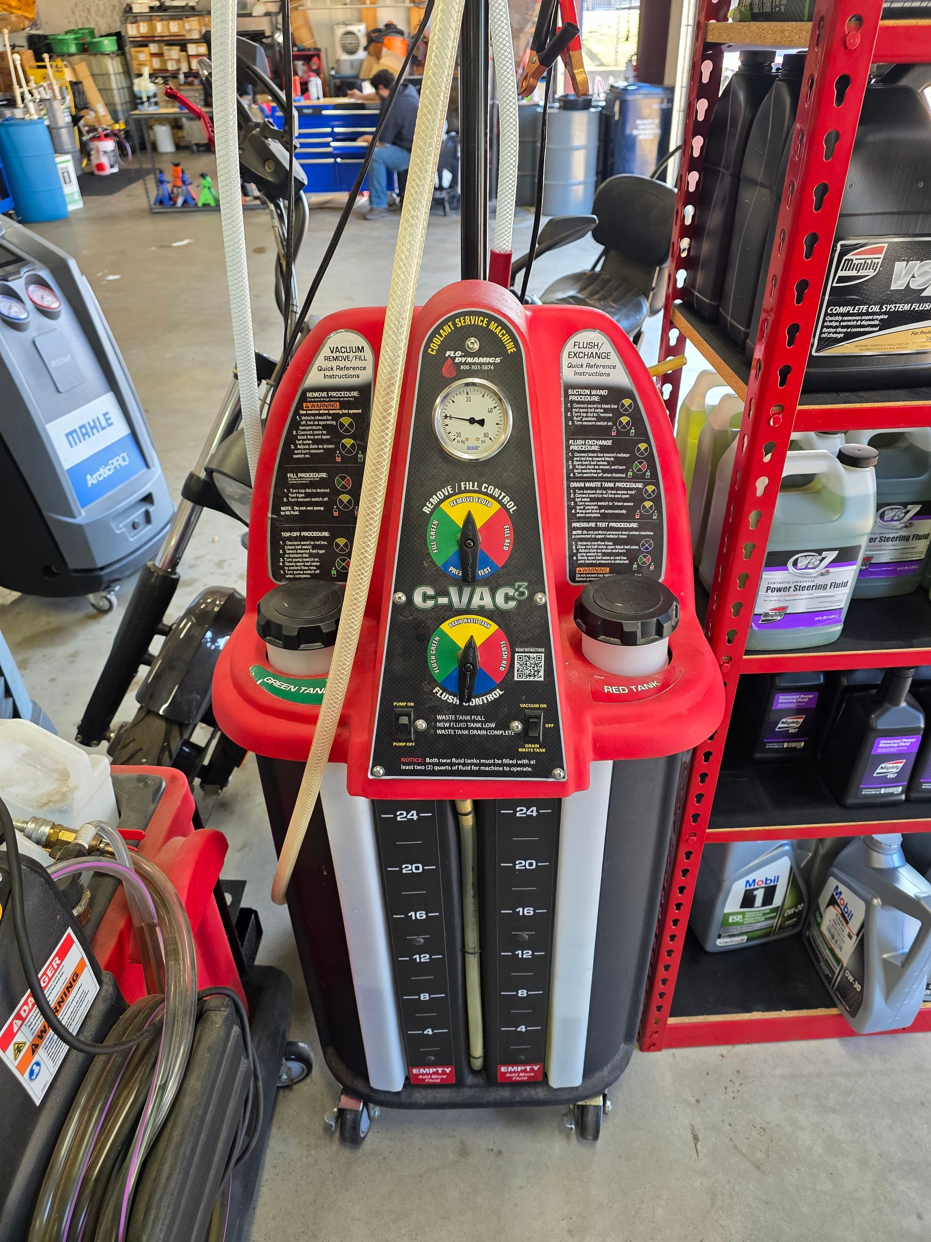 Vacuum coolant exchange machine removing old acidic fluid at Quicker Sticker in College Station to prevent radiator corrosion.