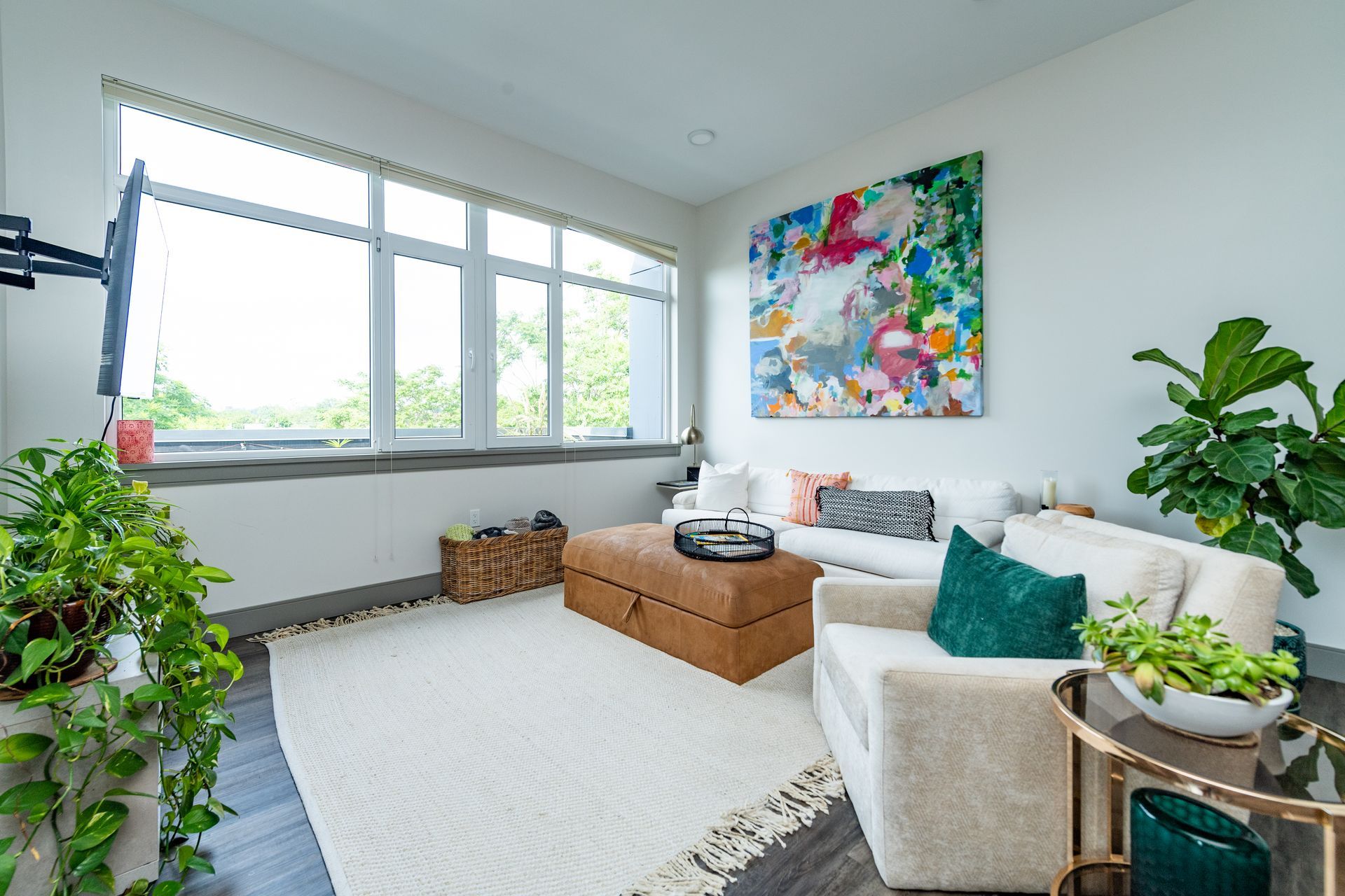 Living room with a white sofa, a large abstract painting, and a large window.