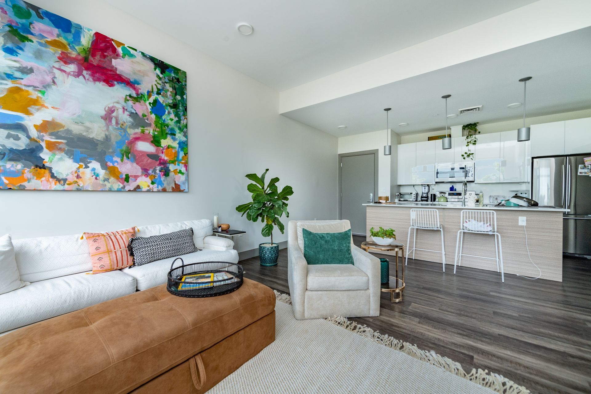 Modern living room with white sofa, colorful art, and open kitchen.