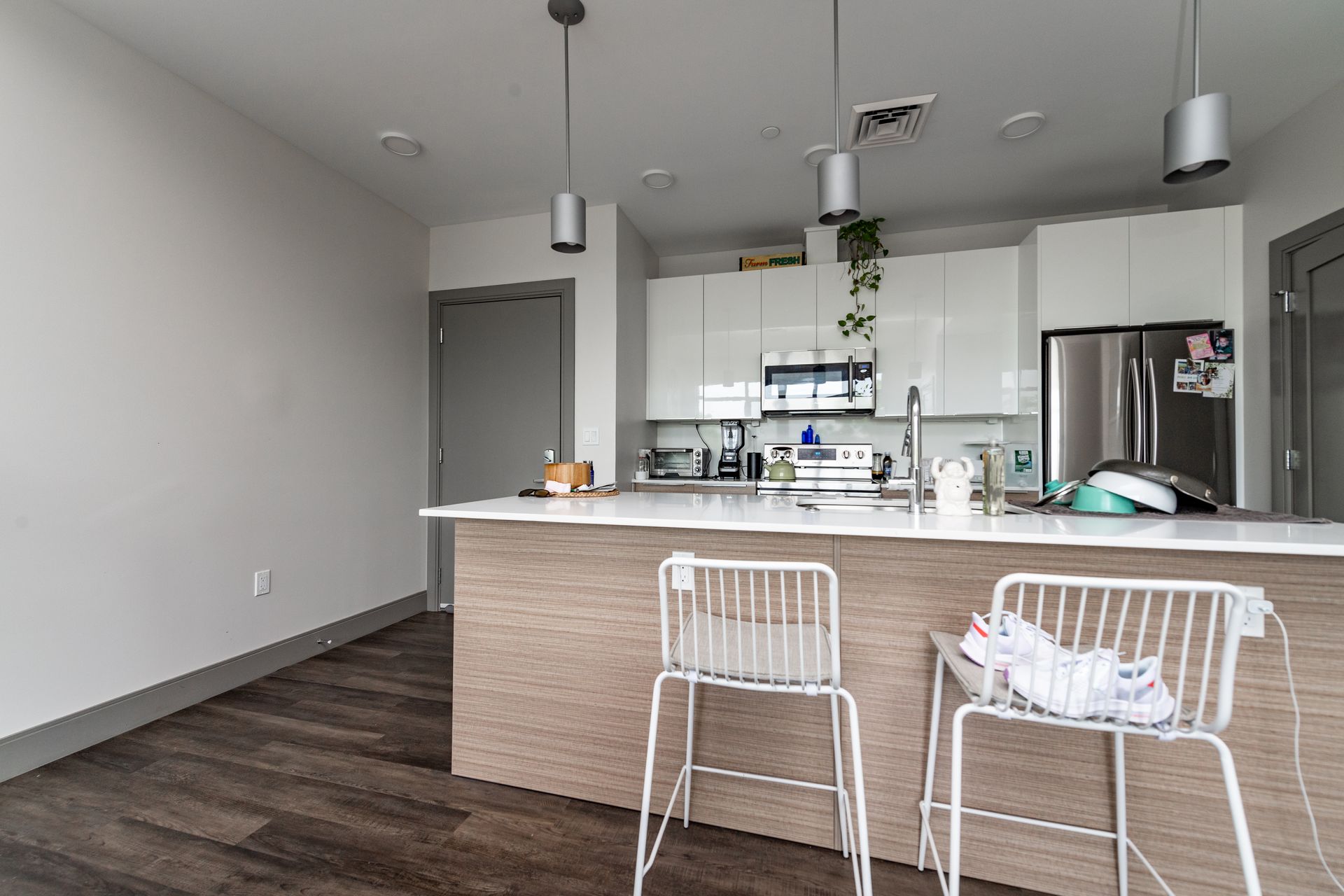 Modern kitchen with white cabinets, island with stools, and stainless steel appliances.