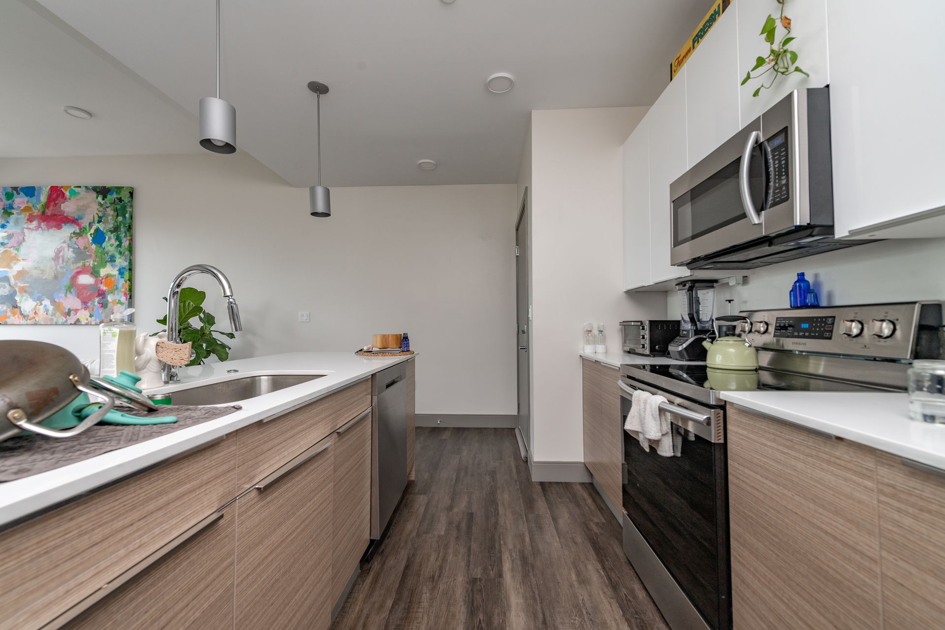 Modern kitchen with white countertops, stainless steel appliances, and wood-tone cabinets.