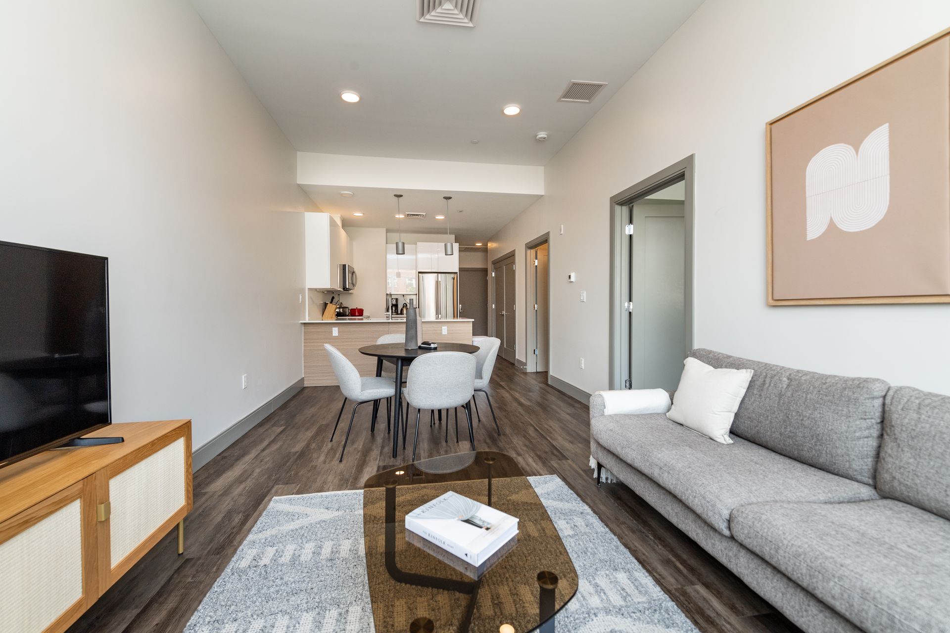 Modern living room with open kitchen, dining area, and gray couch.