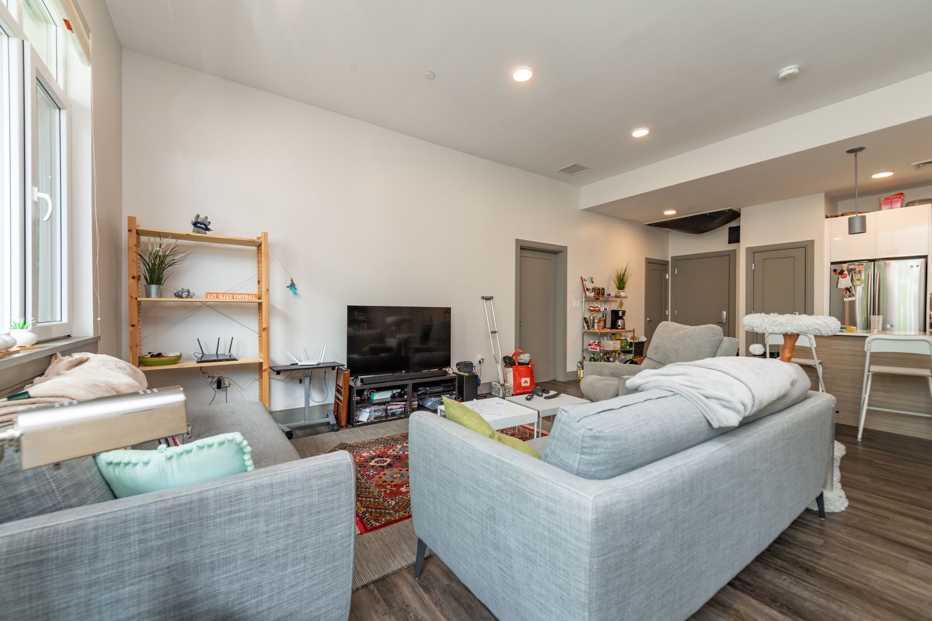 Living room with gray sofas, TV, shelving unit, and a window.
