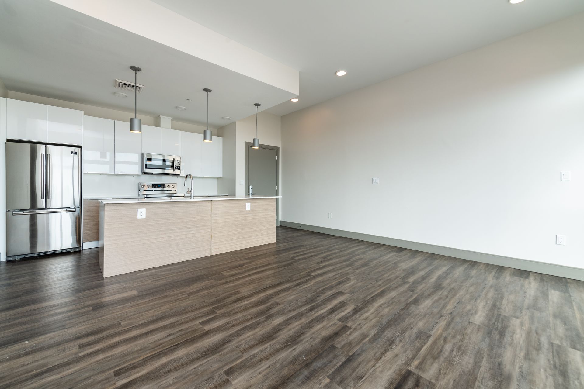 Modern kitchen with white cabinets, stainless steel appliances, and wood floors.