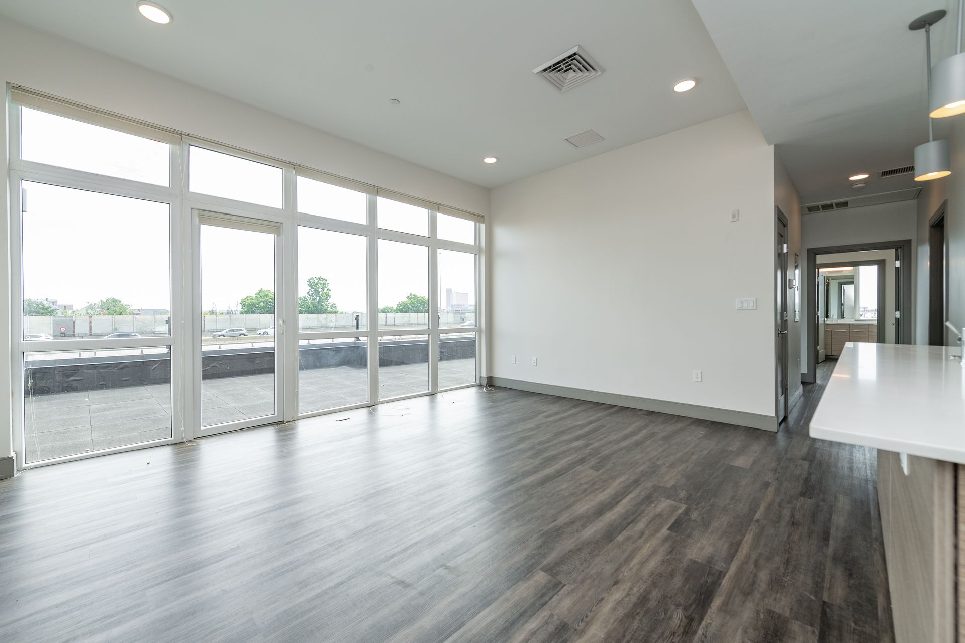 Empty modern living space with large windows overlooking a rooftop patio.