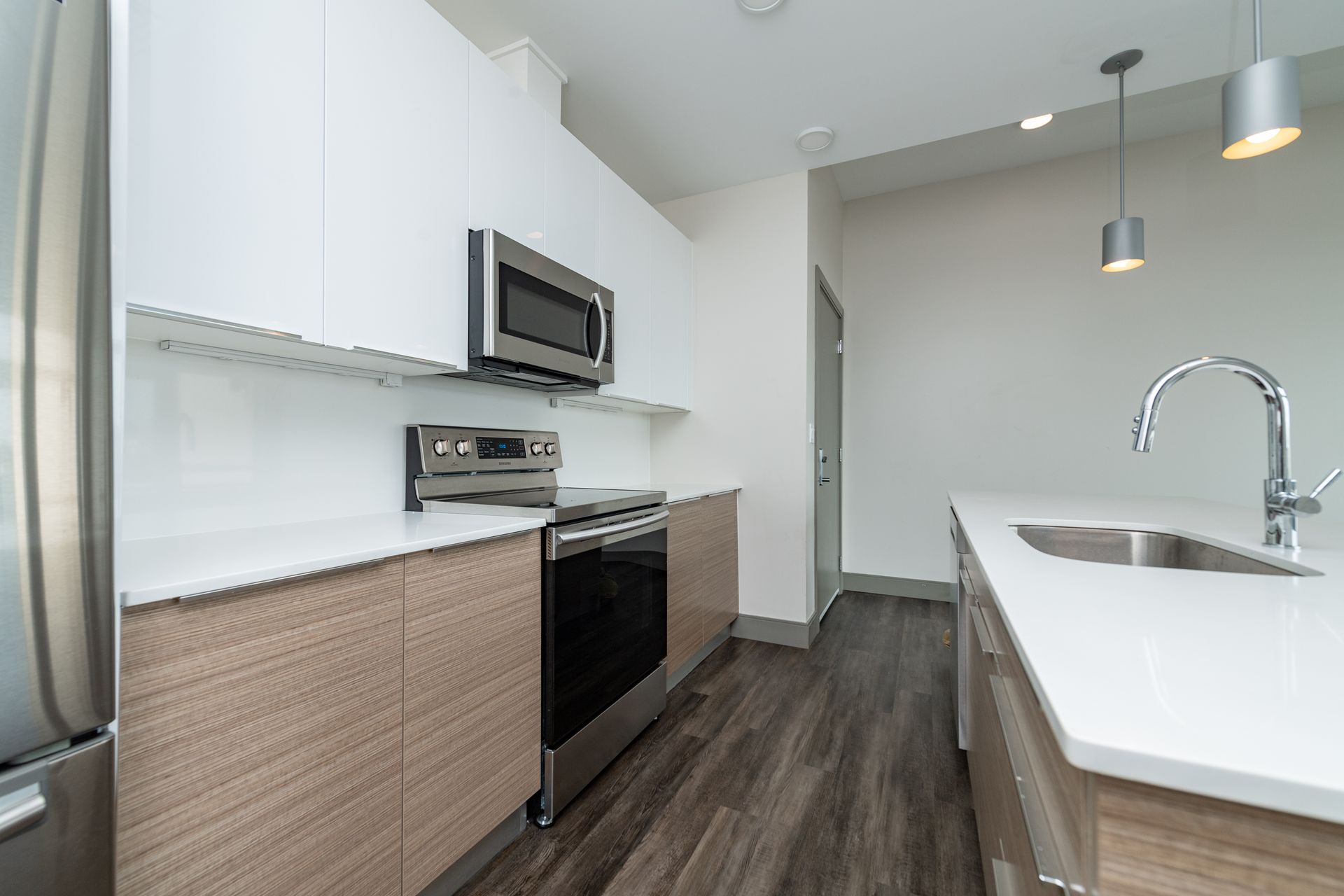 Modern kitchen with white and wood cabinets, stainless steel appliances, and an island with a sink.
