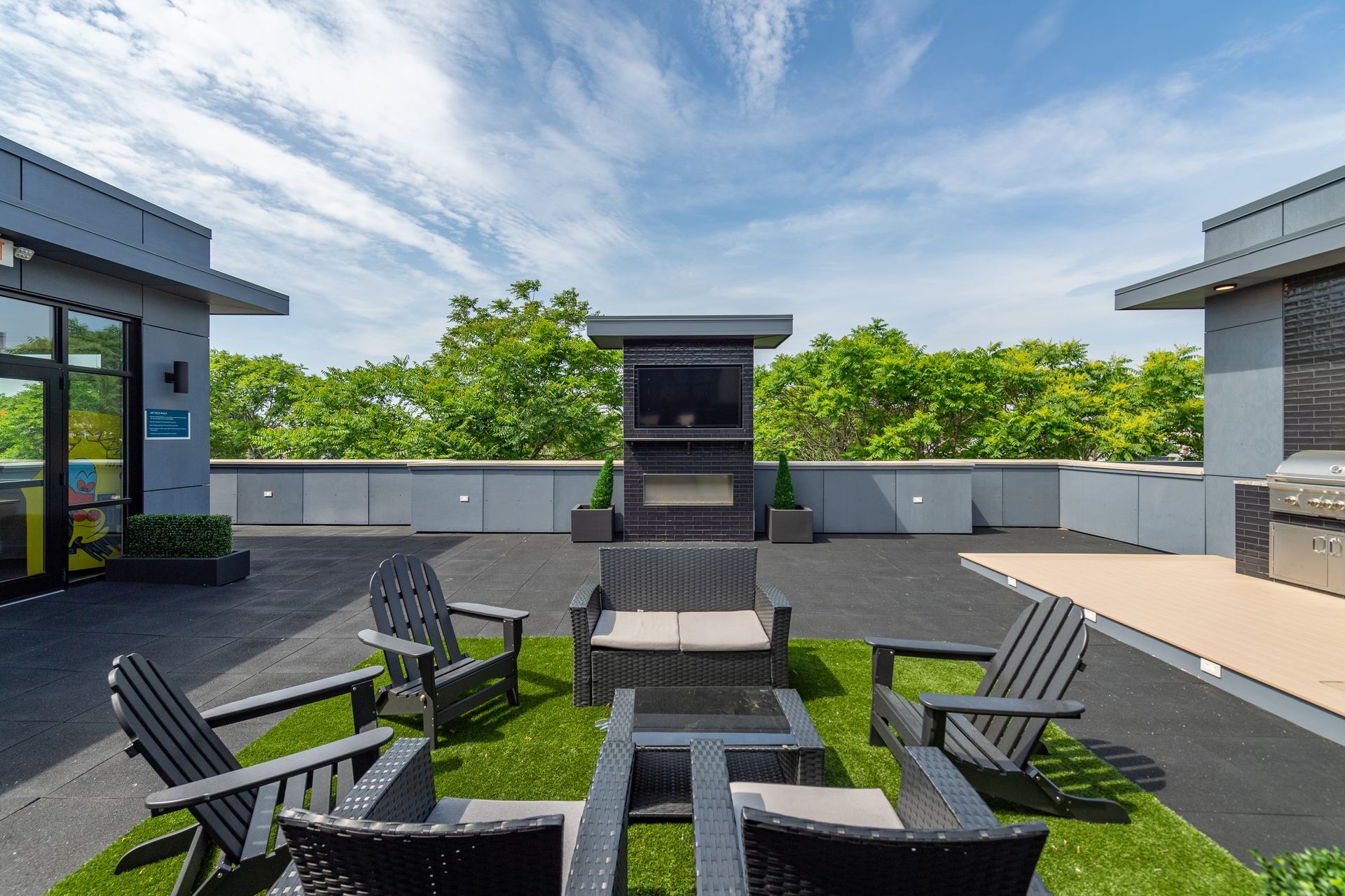 Swimming pool with lounge chairs in front of white apartment buildings under a blue sky.