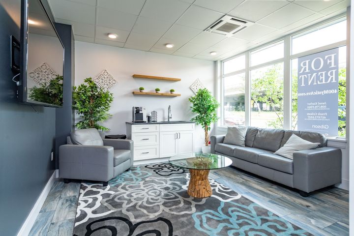 Cozy office waiting area with gray furniture, a floral rug, and a