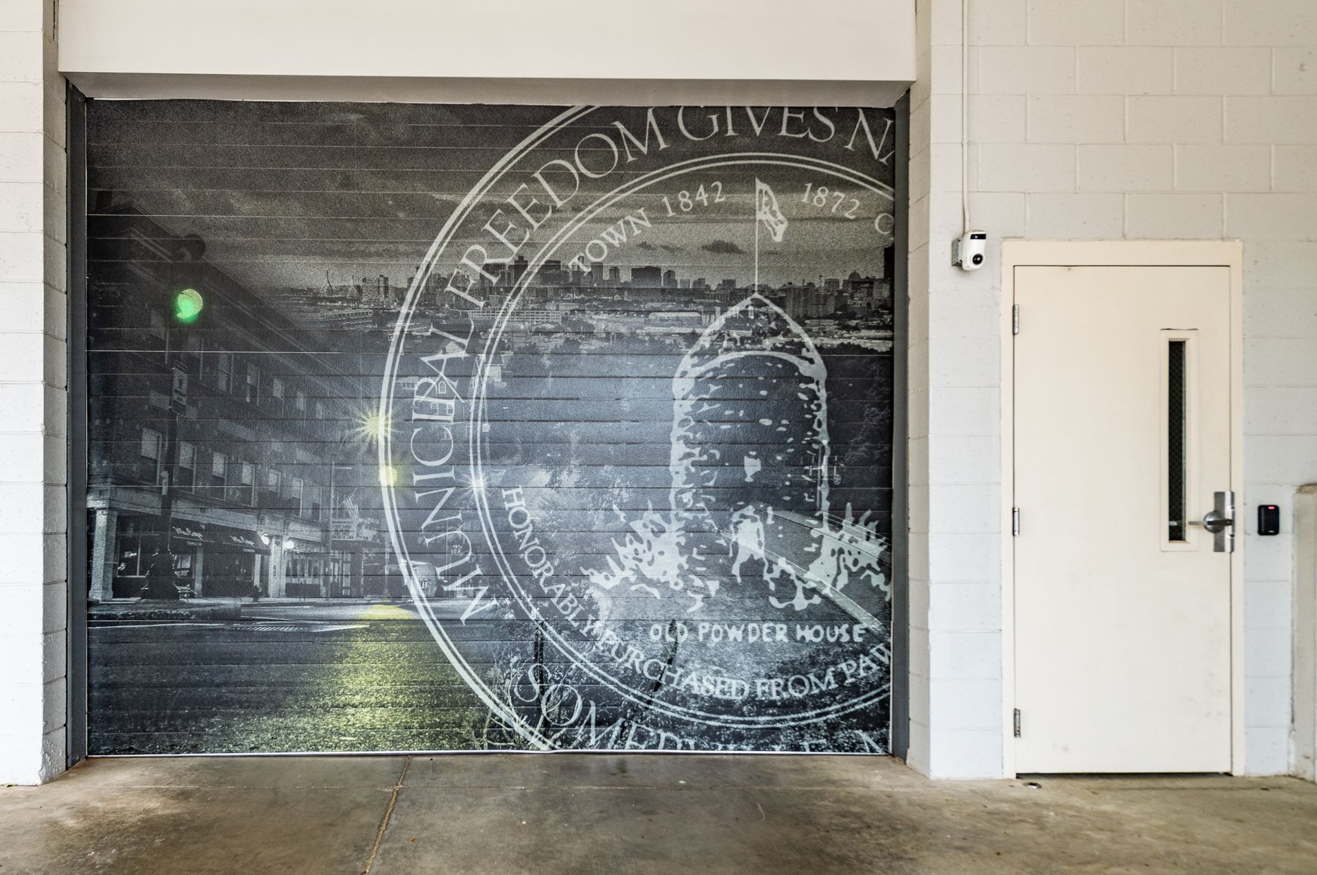 Garage door mural with cityscape and coin design, next to a white door.