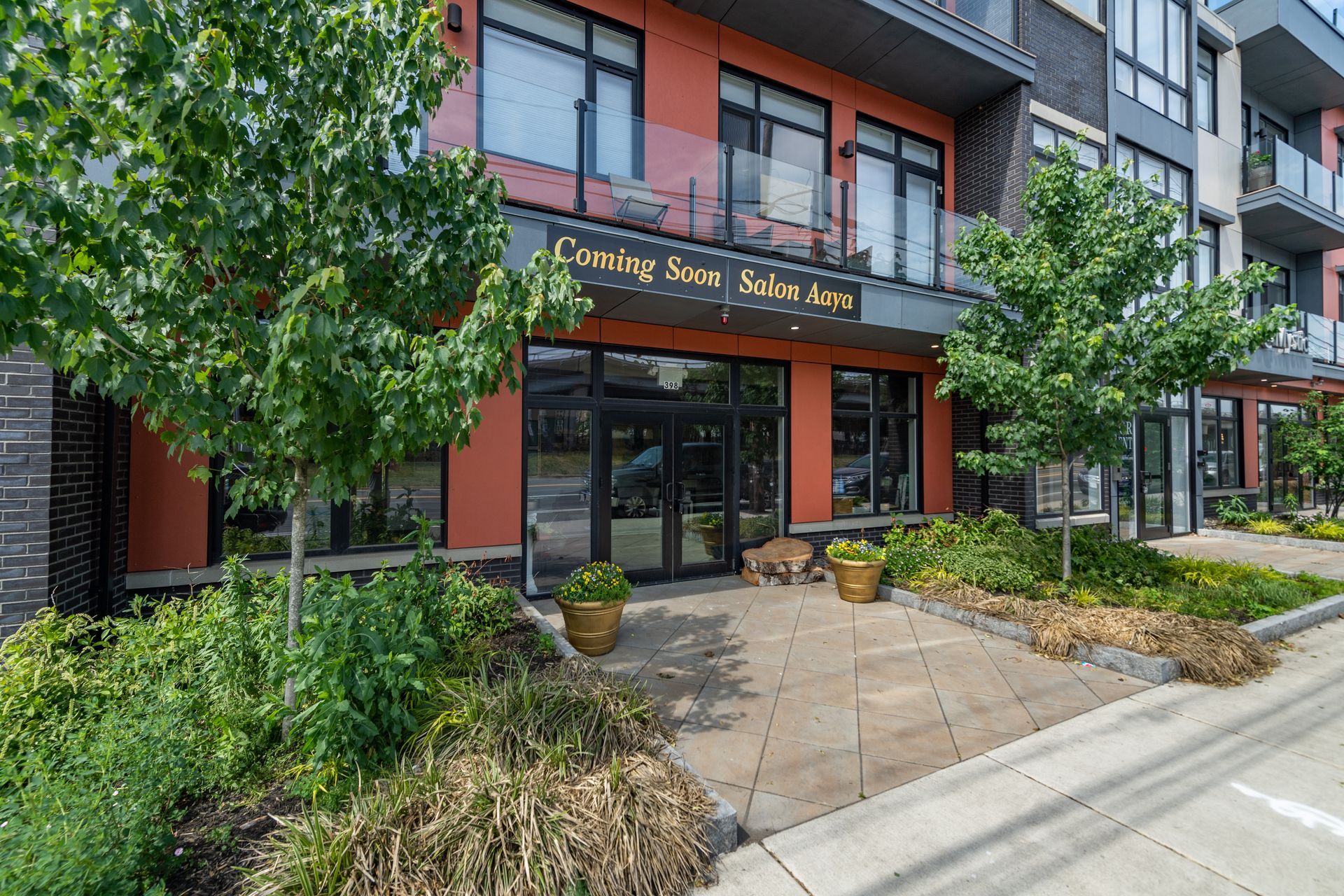 Exterior view of Evening Skies Salon & Acne, a building with glass doors, orange walls, and green trees.