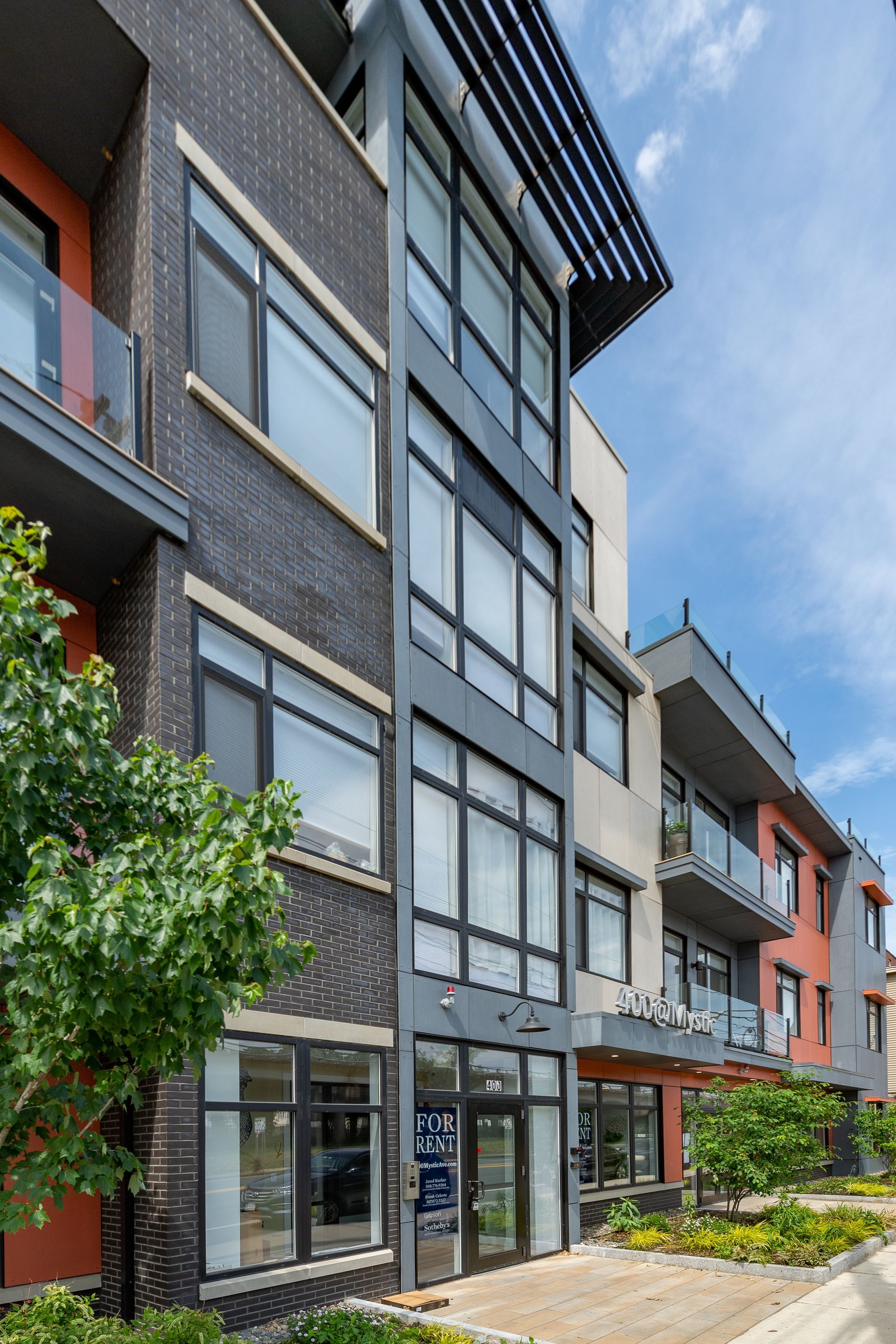 Modern multi-story apartment building with dark brick and gray accents.