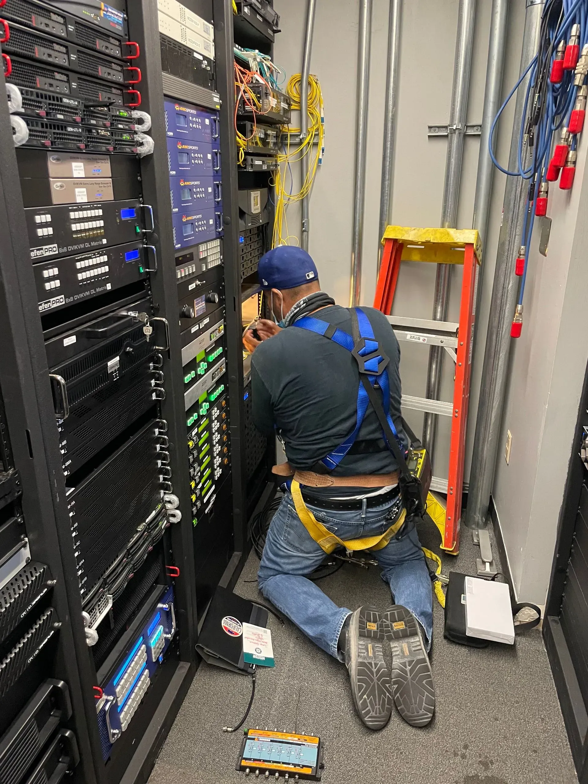 A man is kneeling down in a server room working on a server.