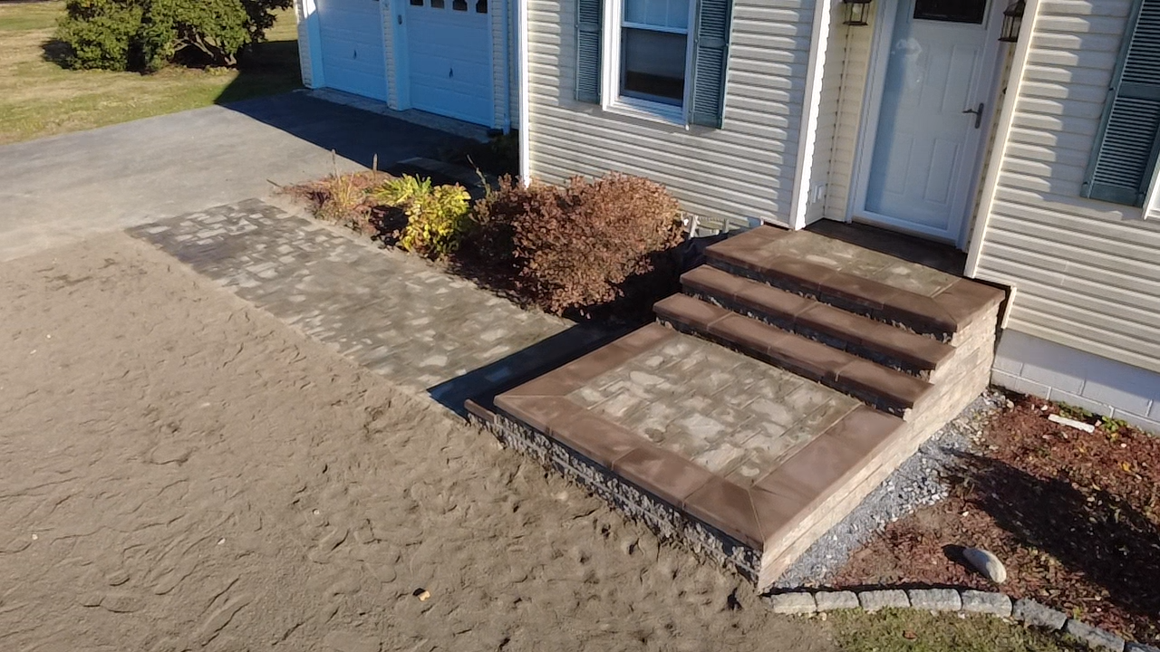 Newly built brick steps and walkway leading to a house with a white door and siding.