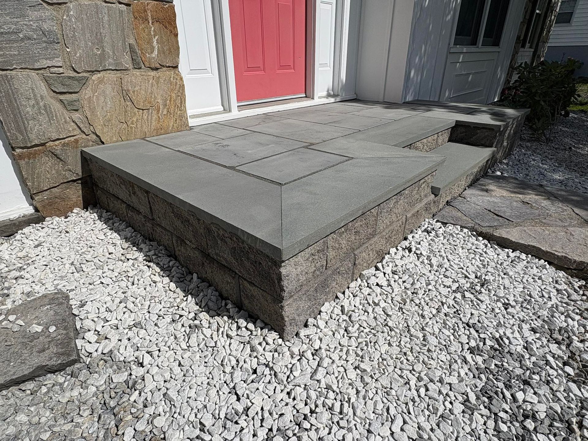 Stone steps leading to a red door, surrounded by gravel.