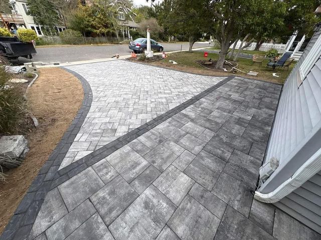 Driveway paved with grey interlocking pavers, with a dark border and gravel edge.