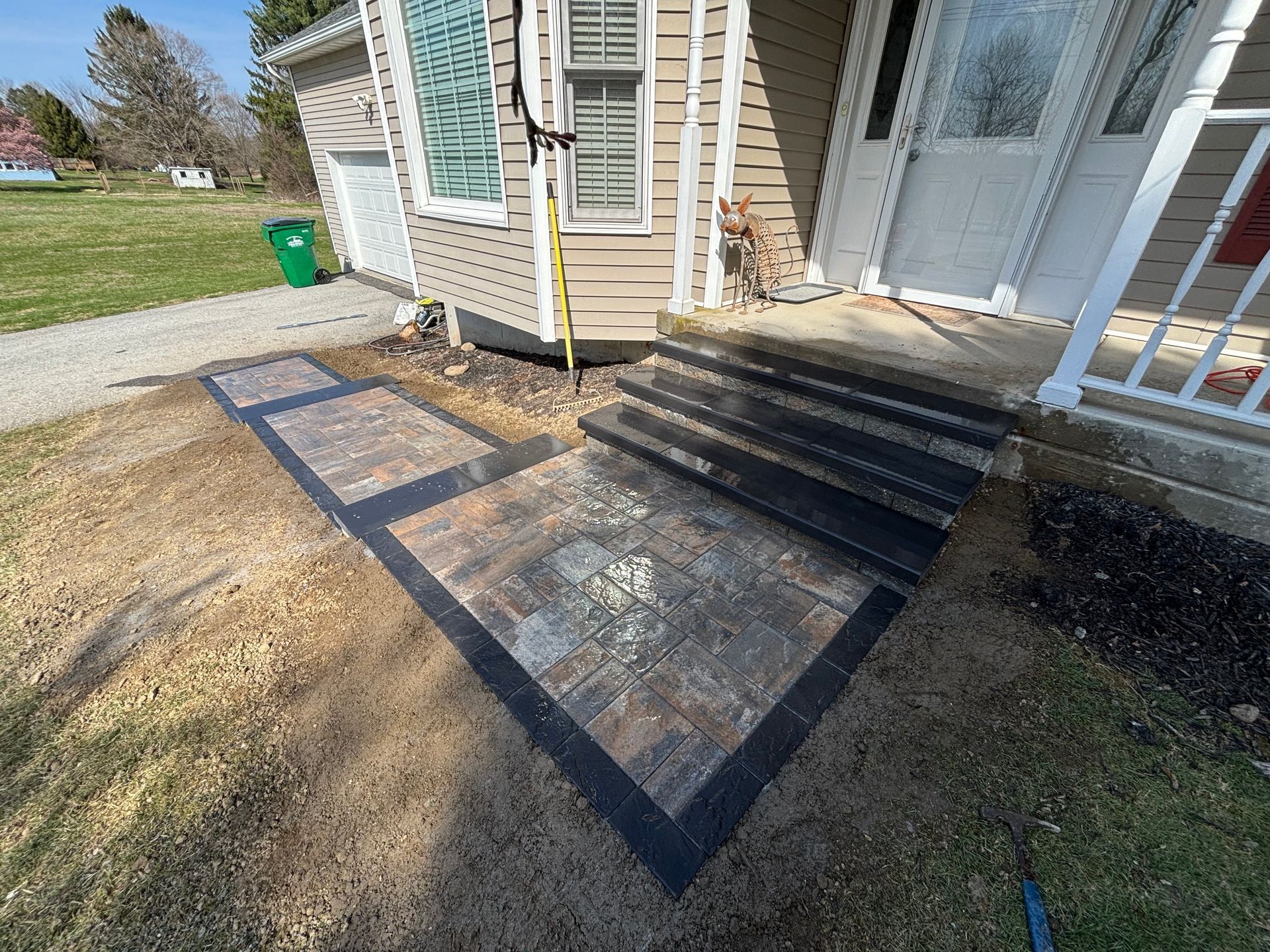 House exterior with concrete steps and patterned paving stones; driveway on left.