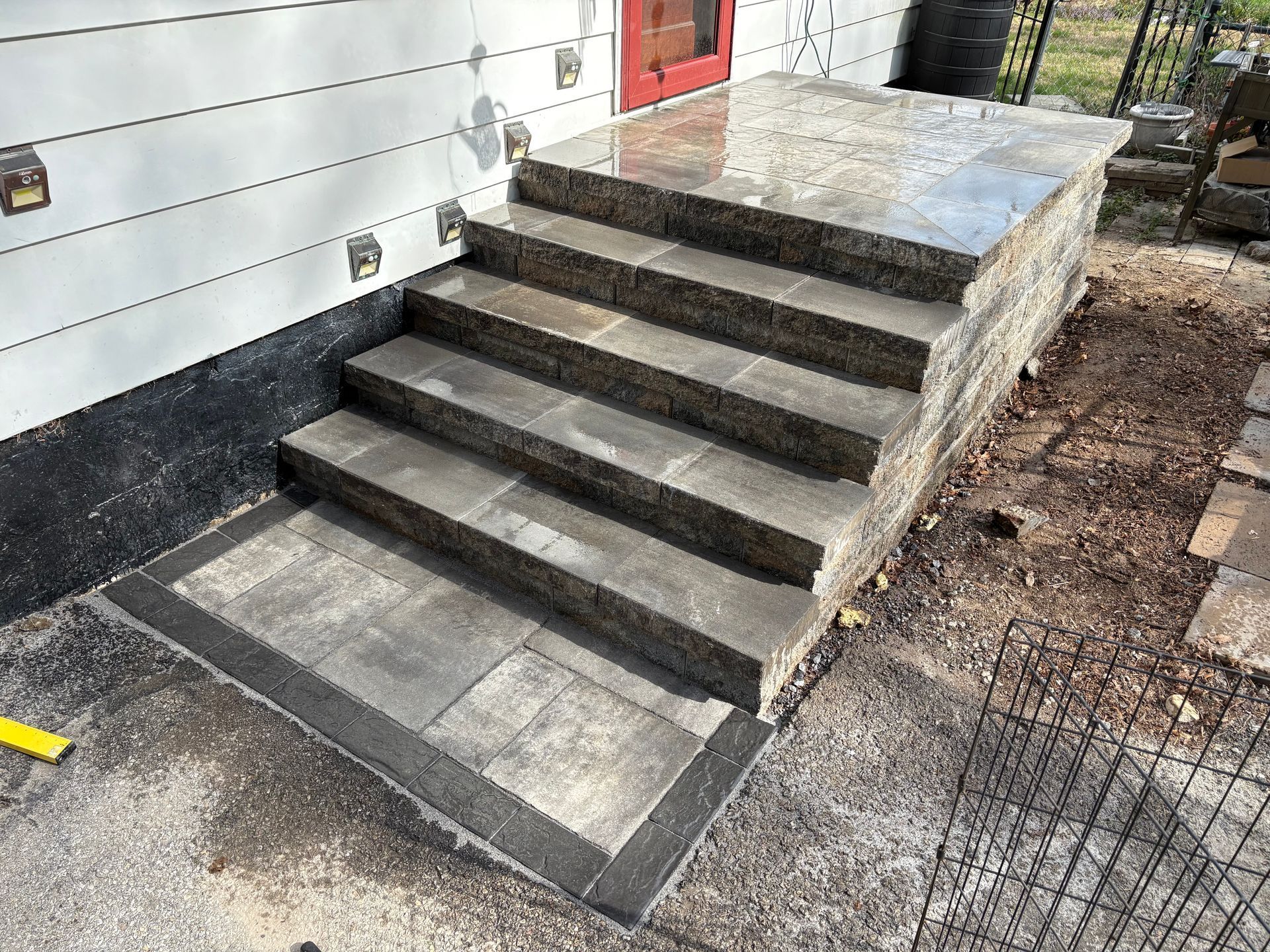 Stone steps leading to a building's entrance. The steps are dark gray and surrounded by exposed earth.