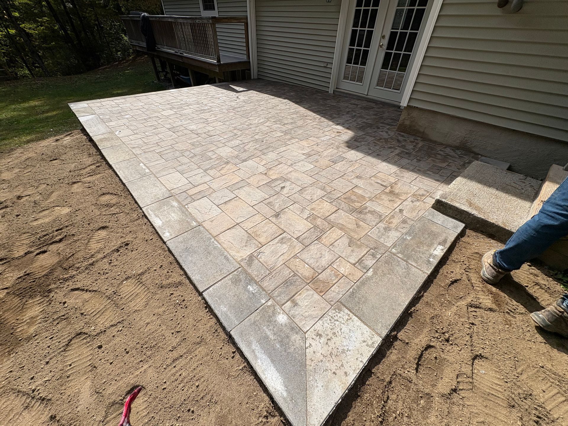 Newly constructed brick patio next to a house with an open doorway.
