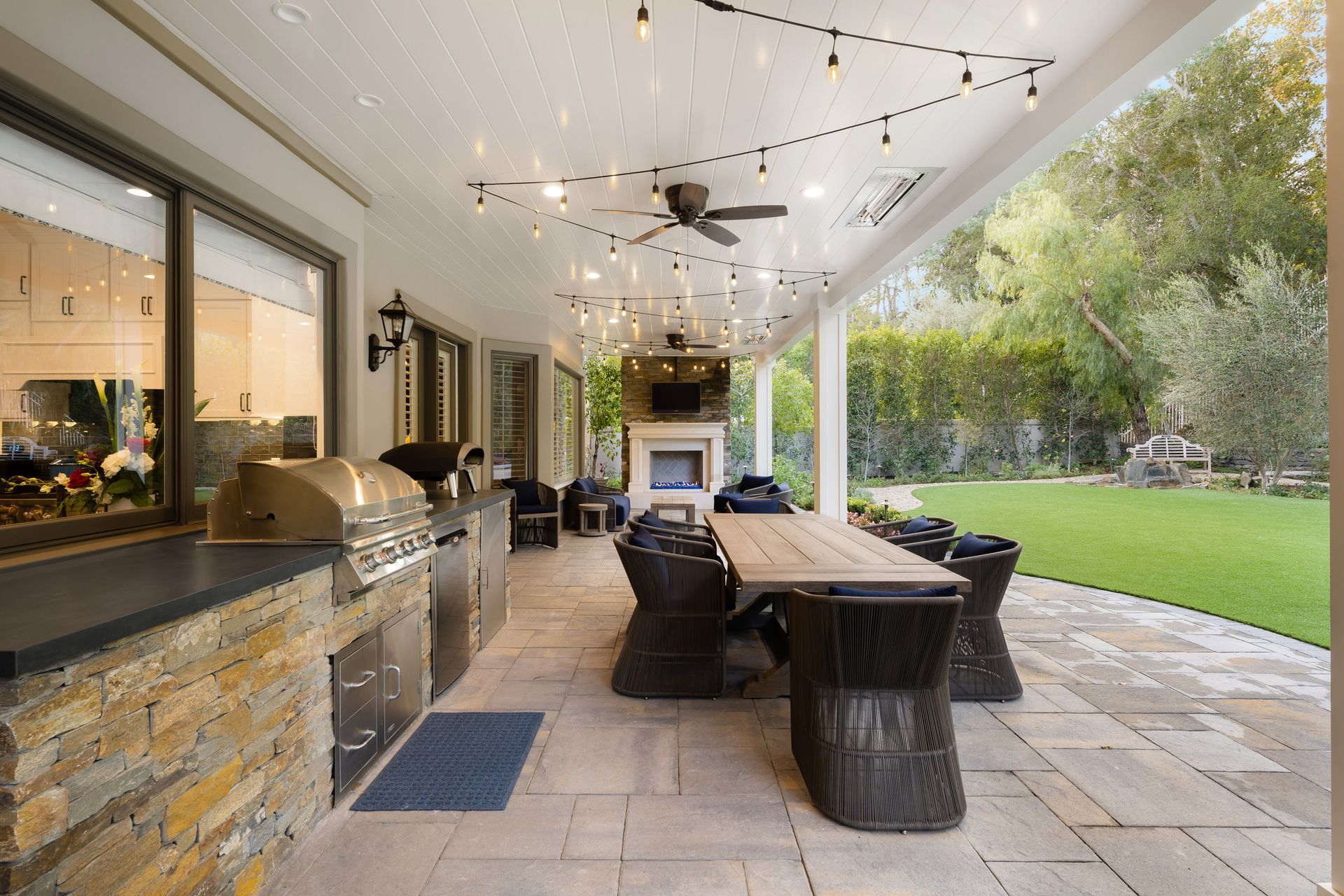 Covered patio with outdoor kitchen, dining table, and backyard.