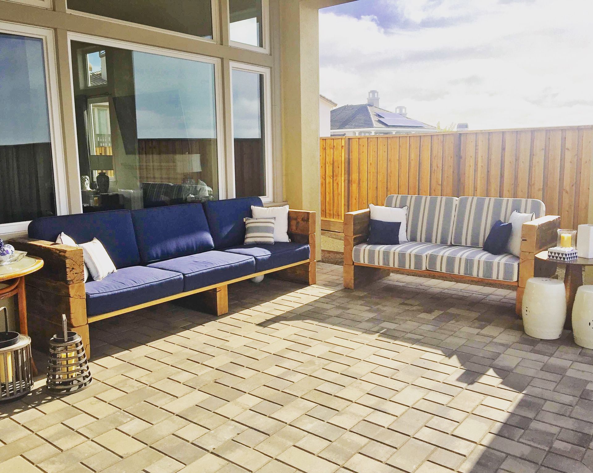 Patio with blue and striped outdoor sofas, wicker chair, and potted decor on a tiled terrace