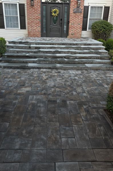 Brick house entrance with stone steps, a dark-colored walkway, and a decorated front door.