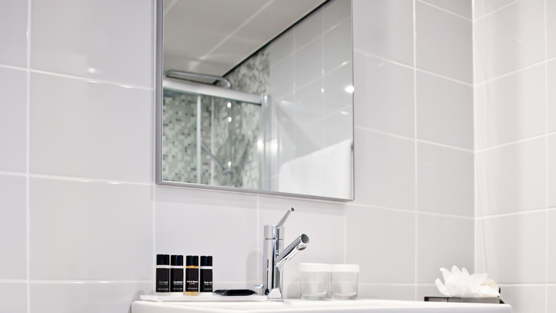 A bathroom with white tiles , a sink and a mirror. — Maryborough Bay Glass & Aluminium in Maryborough, QLD