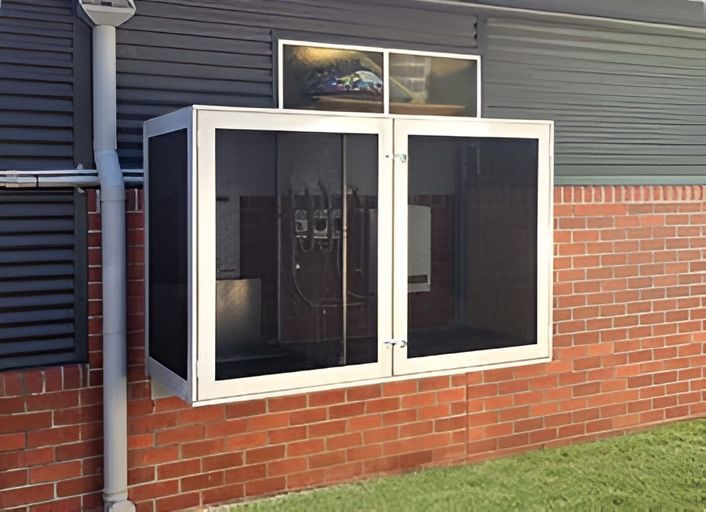 A metal box with screen doors attached to a brick building. The box likely houses equipment, as seen through the screens. — Maryborough Bay Glass & Aluminium in Howard, QLD