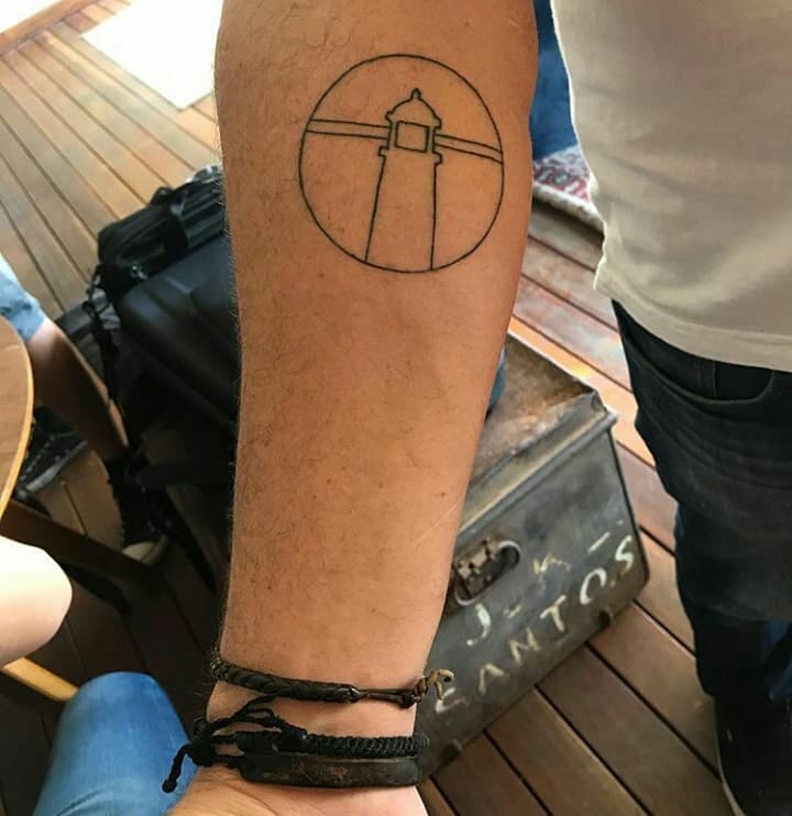 Um homem tem uma tatuagem de um farol no braço