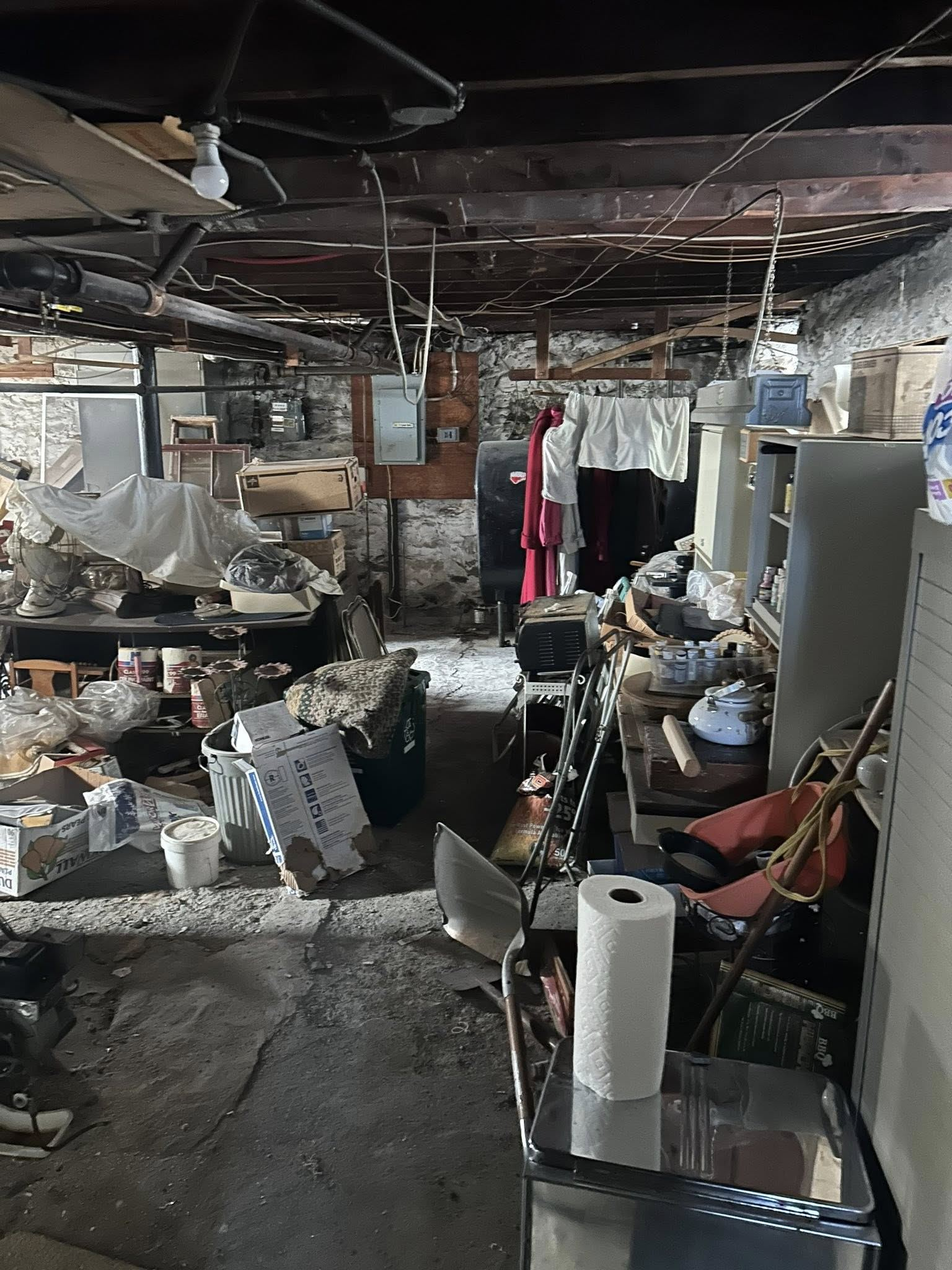 A basement filled with lots of junk and a paper towel on the floor.