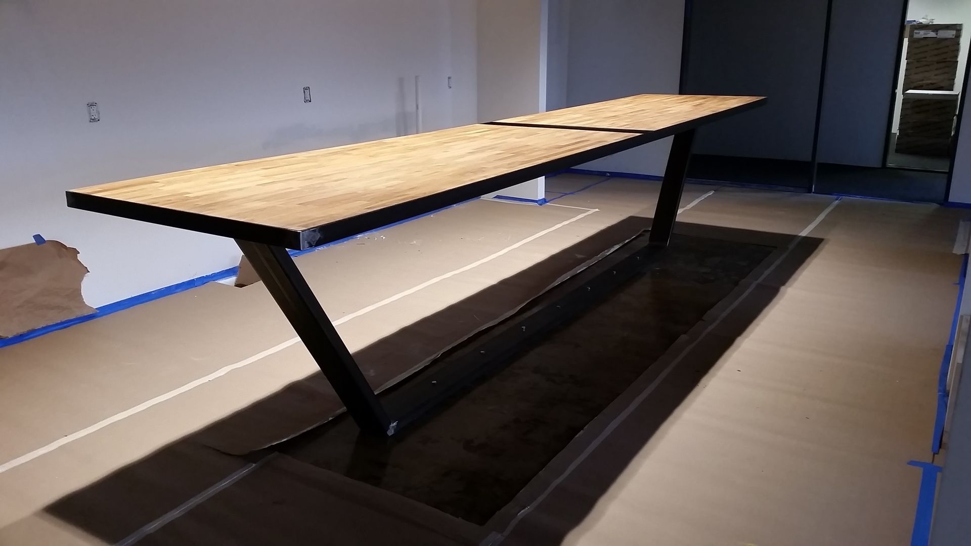 A long wooden table is sitting in a room under construction.