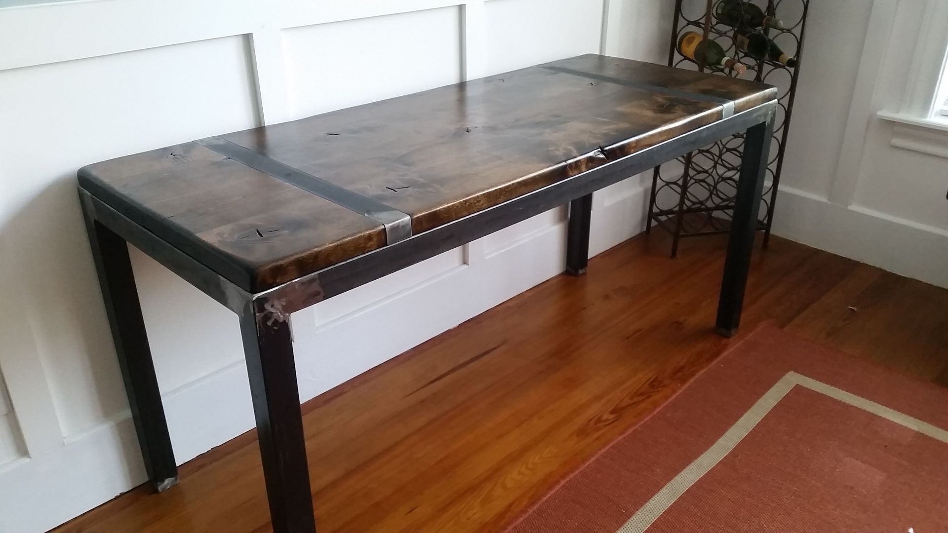 A wooden table with metal legs is sitting on a wooden floor in a room.