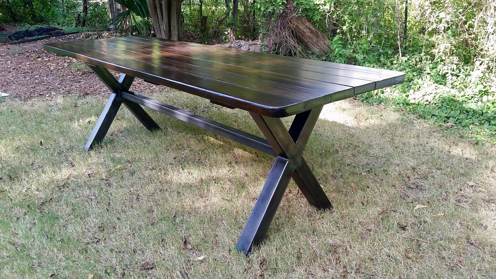 A wooden table is sitting on top of a lush green field.
