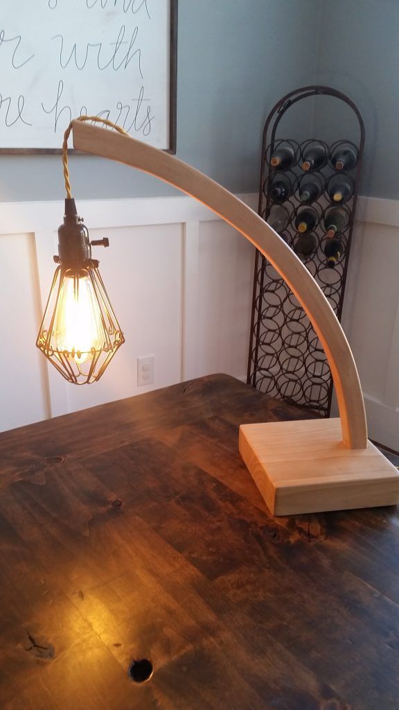 A wooden lamp is sitting on top of a wooden table.