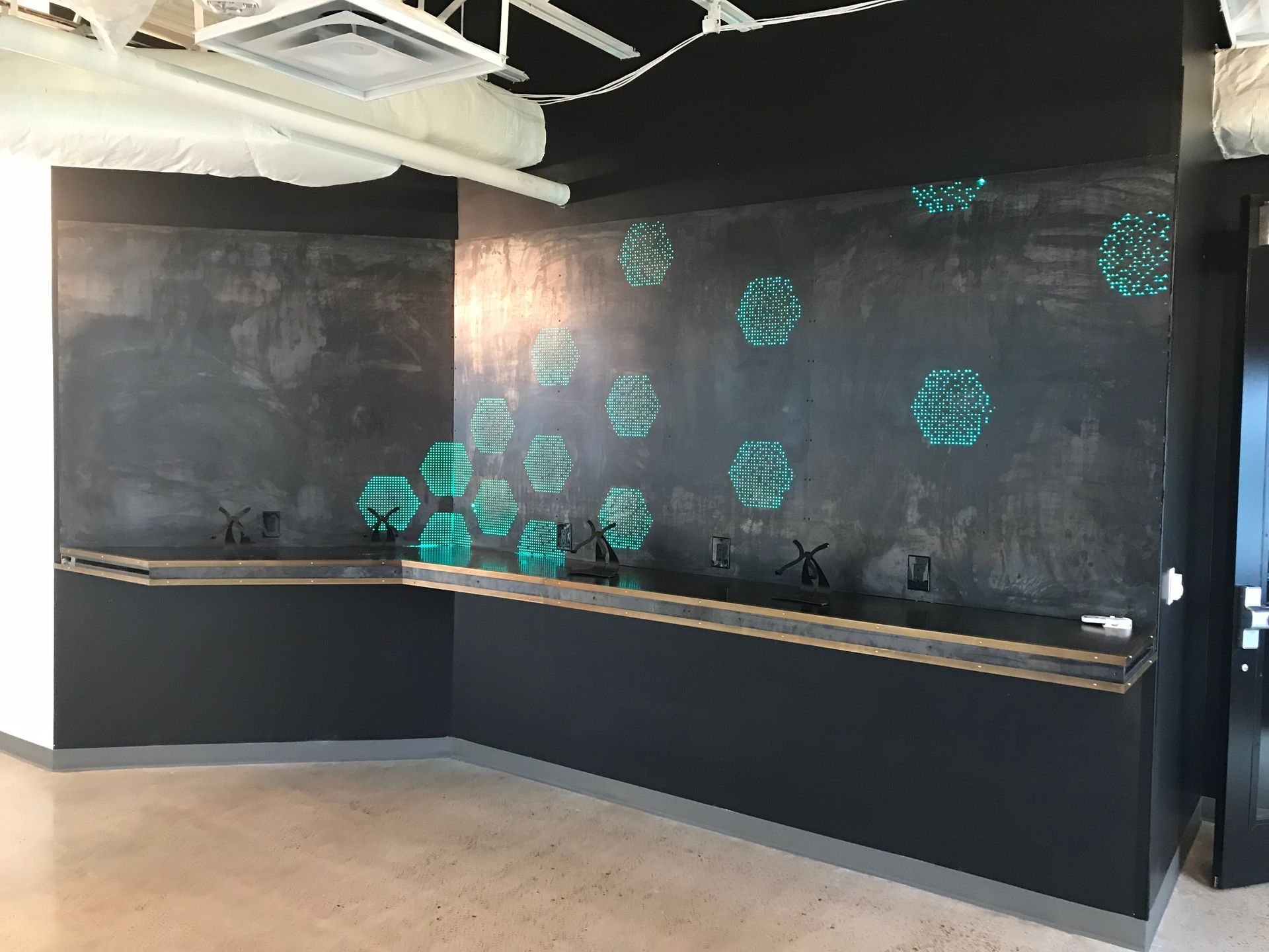 An empty room with a black wall and a wooden floor.