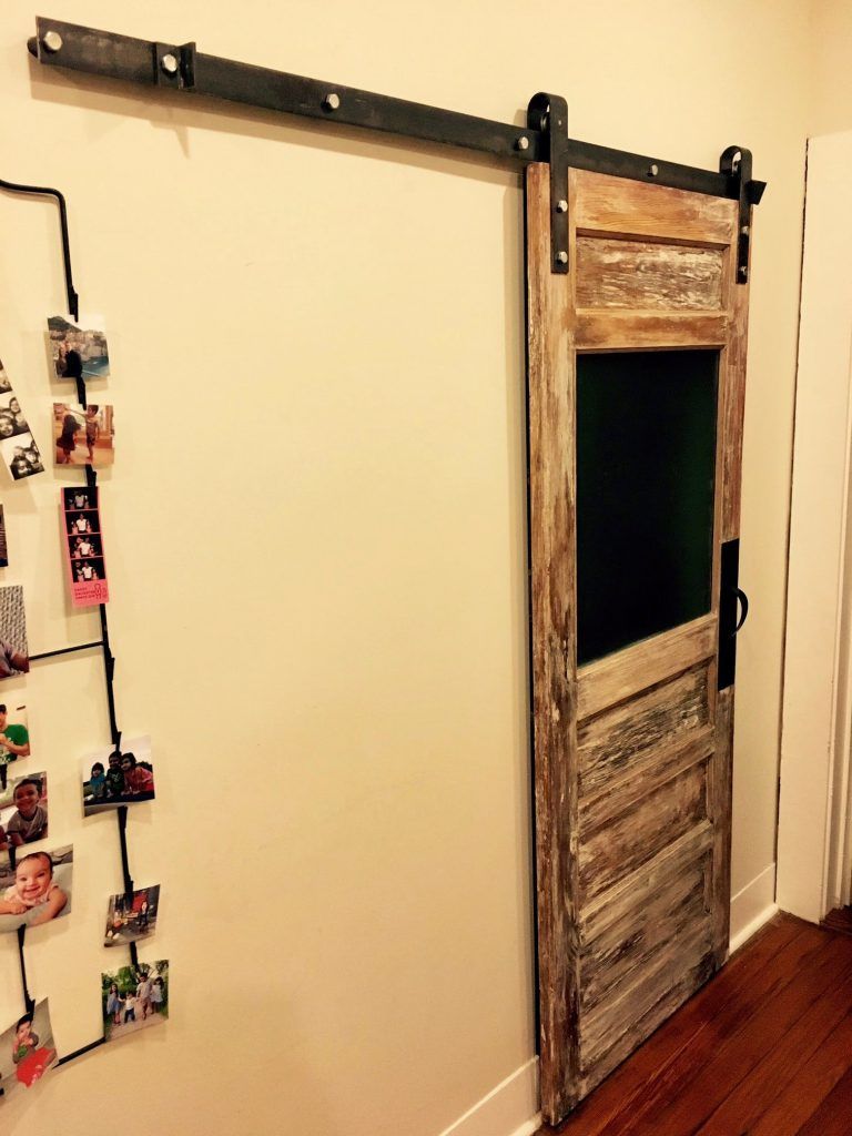 A sliding barn door is hanging on a white wall in a hallway.