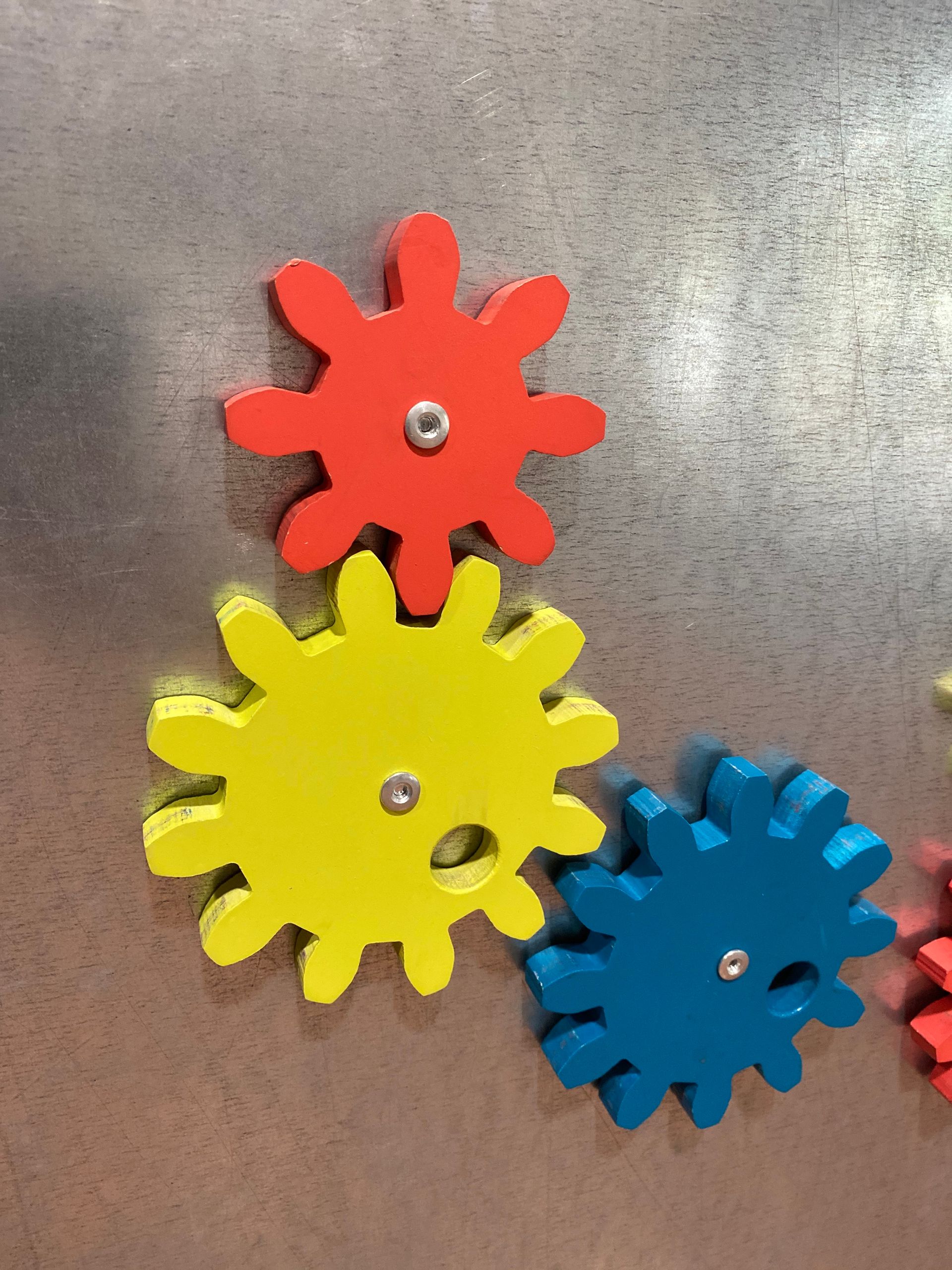 Three colorful wooden gears are stacked on top of each other