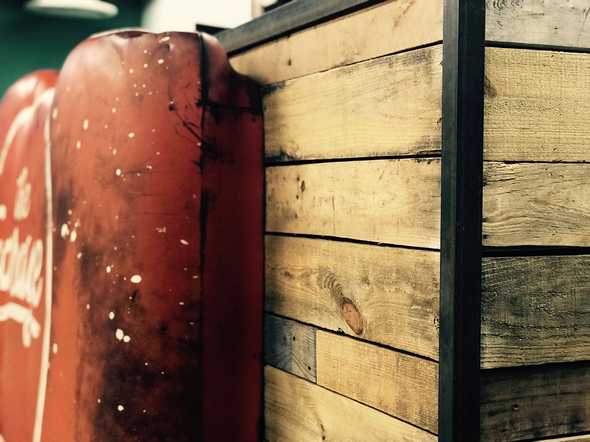 A red coca cola sign is next to a wooden wall